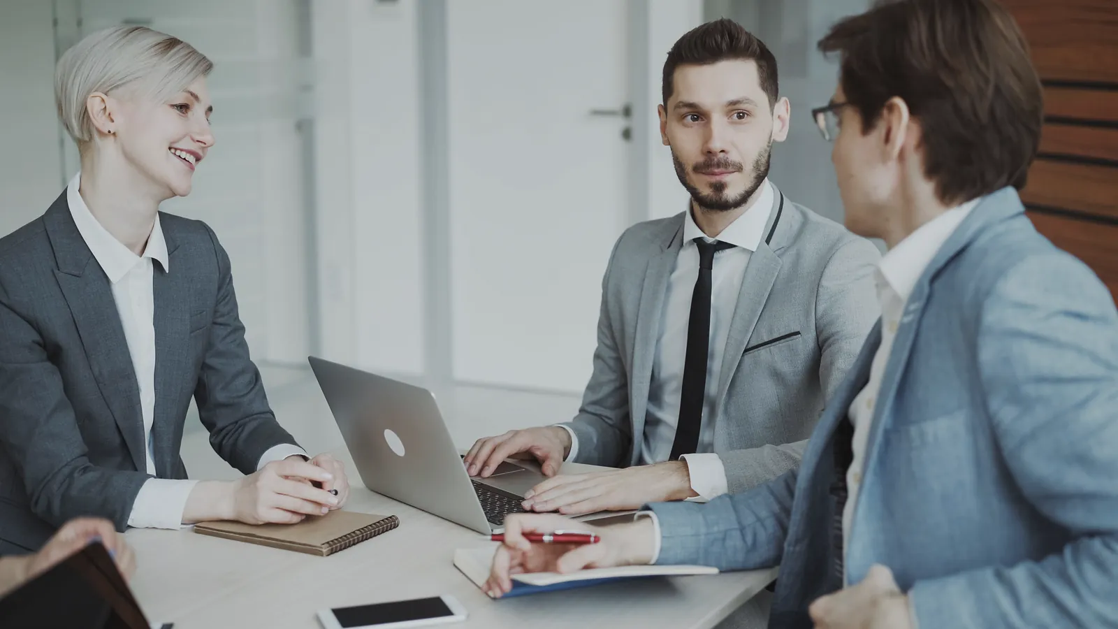 Management team discussing financial plans around a meeting table with a laptop